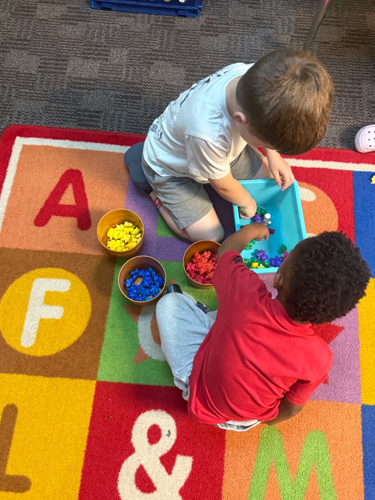 Children sorting bear counters by color into small buckets