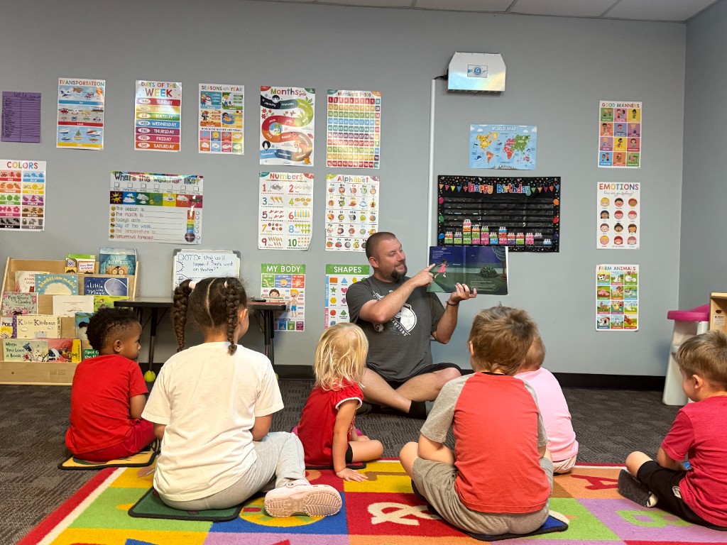 A teacher reading a picture book to a group of children during storytime at For A Child